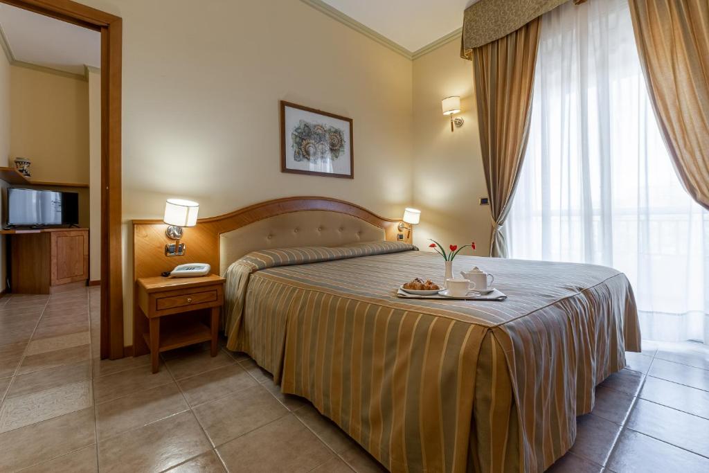 a hotel room with a bed with a tray of food on it at Hotel Relax in Siracusa