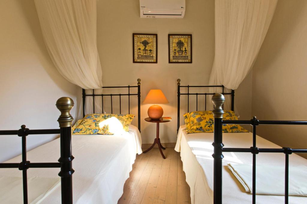 a bedroom with two beds and a table with a lamp at Casa Paleopolis in Corfu Town