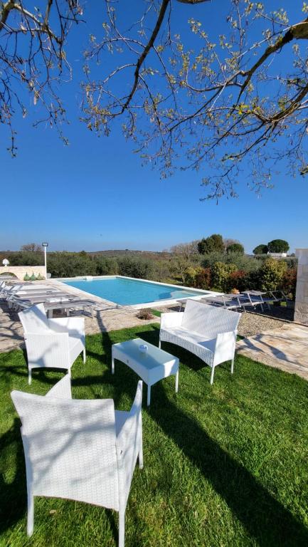 een groep witte stoelen in het gras naast een zwembad bij Casa Relax Isabelle in Alberobello