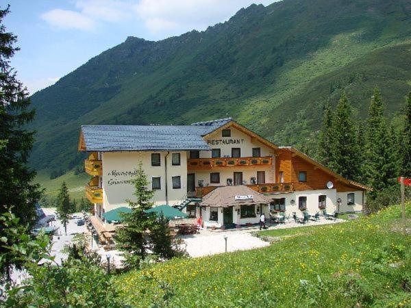 ein großes Gebäude auf einem Hügel mit einem Berg in der Unterkunft Alpengasthof Grimmingblick in Planneralm
