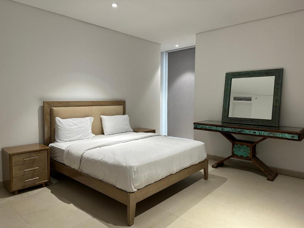 a bedroom with a bed and a mirror and a table at One Constitution Avenue by Goldfinch in Islamabad