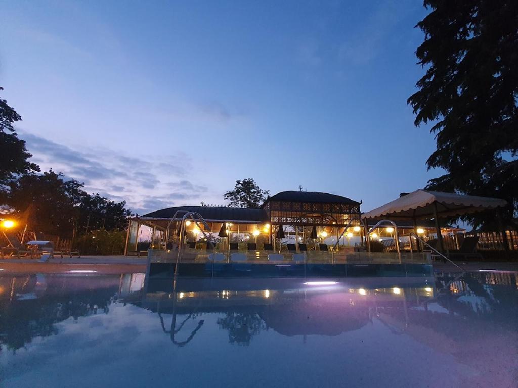 a large building with a pool of water at night at Hotel Villa Beccaris in Monforte dʼAlba