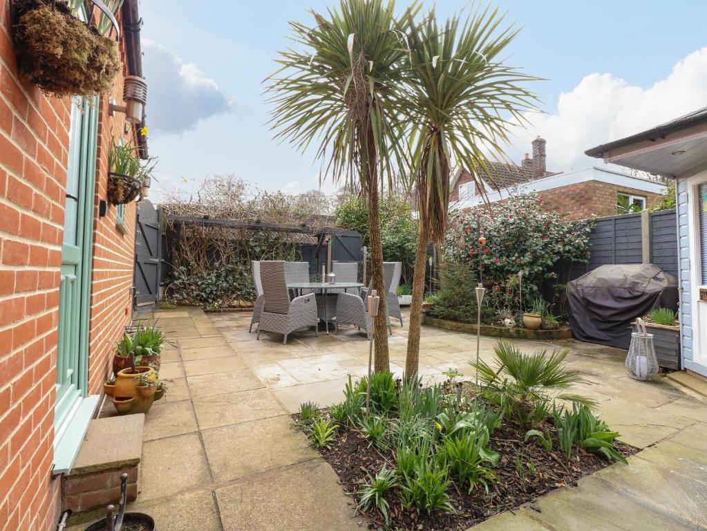 a patio with a palm tree and a table and chairs at Primose Cottage in Cromer