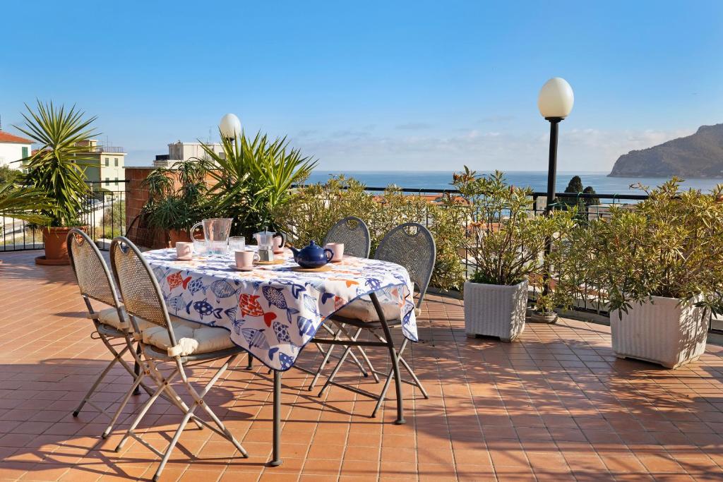 een tafel en stoelen op een patio met de oceaan op de achtergrond bij Attico Cielo e mare in Spotorno