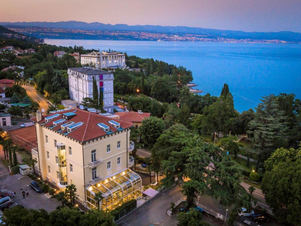 un edificio con techo rojo junto a una masa de agua en Hotel Villa Eugenia, en Lovran