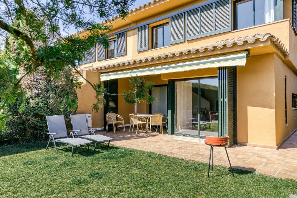 Casa con patio con sillas y mesa en Family villa in Torremirona Resort en Navata