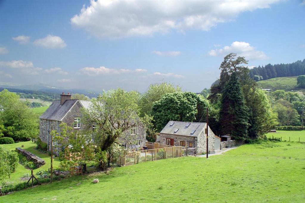 an old house on a hill with a green field at The Coach House in Penmachno