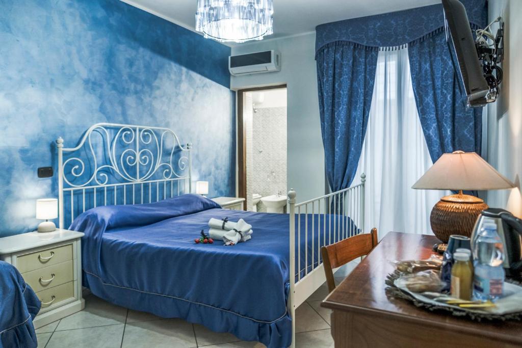 ein blaues Schlafzimmer mit einem Bett und einem Schreibtisch in der Unterkunft Spartacus in Santa Maria Capua Vetere