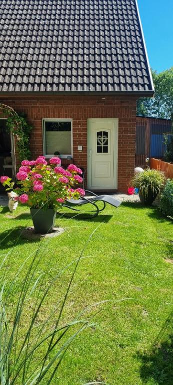 a yard with a house with pink flowers in the grass at Ferienwohnung Möwennest in Wangerland