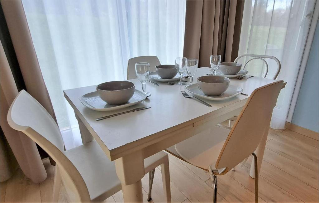 a white table with chairs and bowls and wine glasses at Awesome Apartment In quemauville With Outdoor Swimming Pool, Heated Swimming Pool And 1 Bedrooms in Équemauville