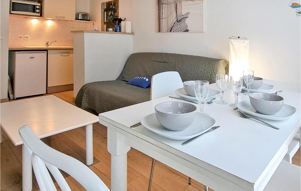 a white dining room table with bowls and plates on it at Awesome Apartment In quemauville With Outdoor Swimming Pool, Heated Swimming Pool And 1 Bedrooms in Équemauville