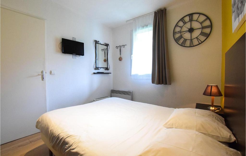 a bedroom with a bed and a clock on the wall at Awesome Apartment In quemauville With Outdoor Swimming Pool, Heated Swimming Pool And 1 Bedrooms in Équemauville