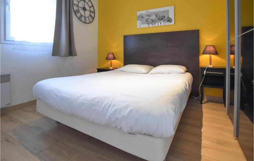 a bedroom with a large bed and a clock on the wall at Awesome Apartment In quemauville With Outdoor Swimming Pool, Heated Swimming Pool And 1 Bedrooms in Équemauville