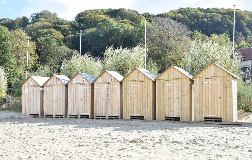 a row of wooden beach huts on a beach at Awesome Apartment In quemauville With Outdoor Swimming Pool, Heated Swimming Pool And 1 Bedrooms in Équemauville