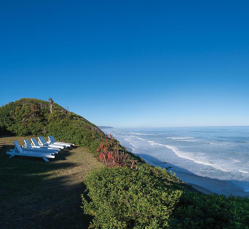 una fila de sillas sentadas en una colina junto al océano en Aquarius Beach House, en Wilderness