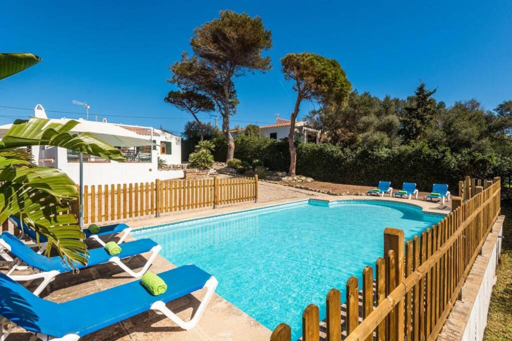 a swimming pool with two blue chairs and a fence at Sa Lluna in Binibeca