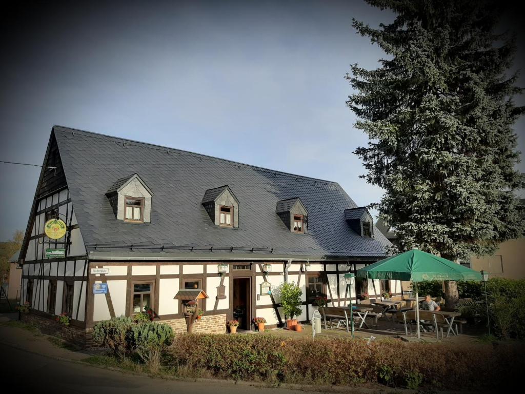 ein großes Haus mit einem Tisch und Stühlen davor in der Unterkunft Wirtschaft & Pension Zum Huthaus in Schneeberg