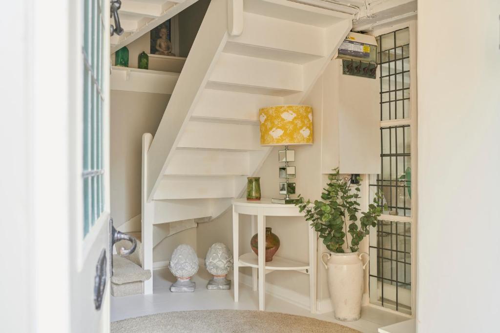 a white staircase in a room with a potted plant at Boutique Chic In Blockley in Blockley