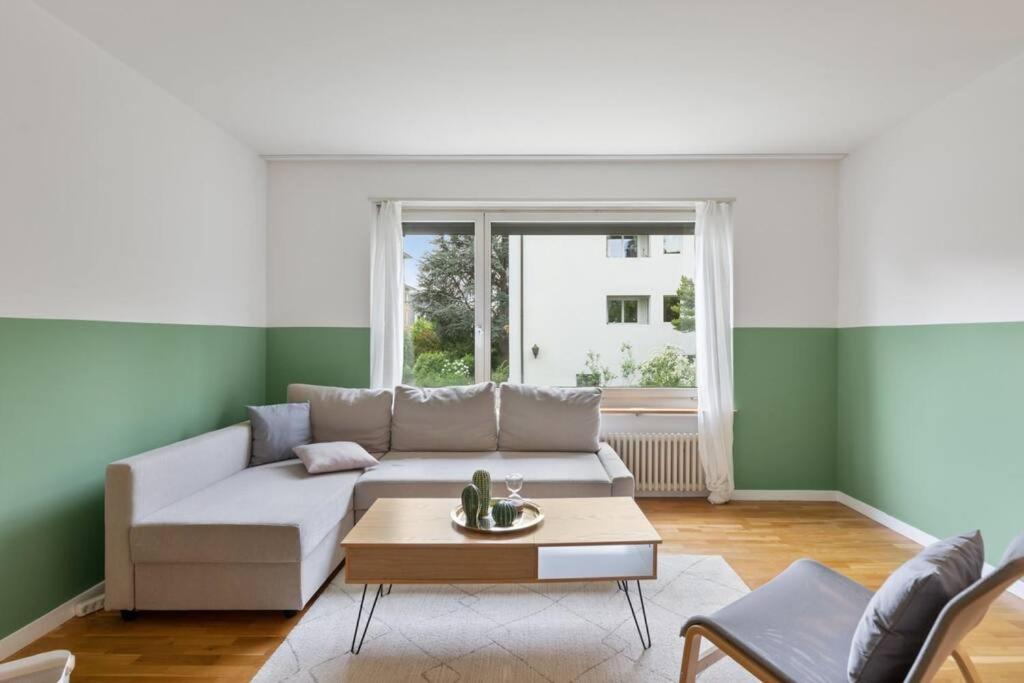 ein Wohnzimmer mit einem weißen Sofa und einem Tisch in der Unterkunft Bethaniaweg in Rüschlikon
