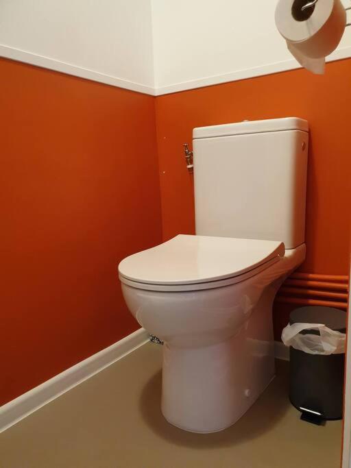 a white toilet in a bathroom with orange walls at Le Nid des Anges, votre studio à la campagne. in Saint-Laurent-du-Plan
