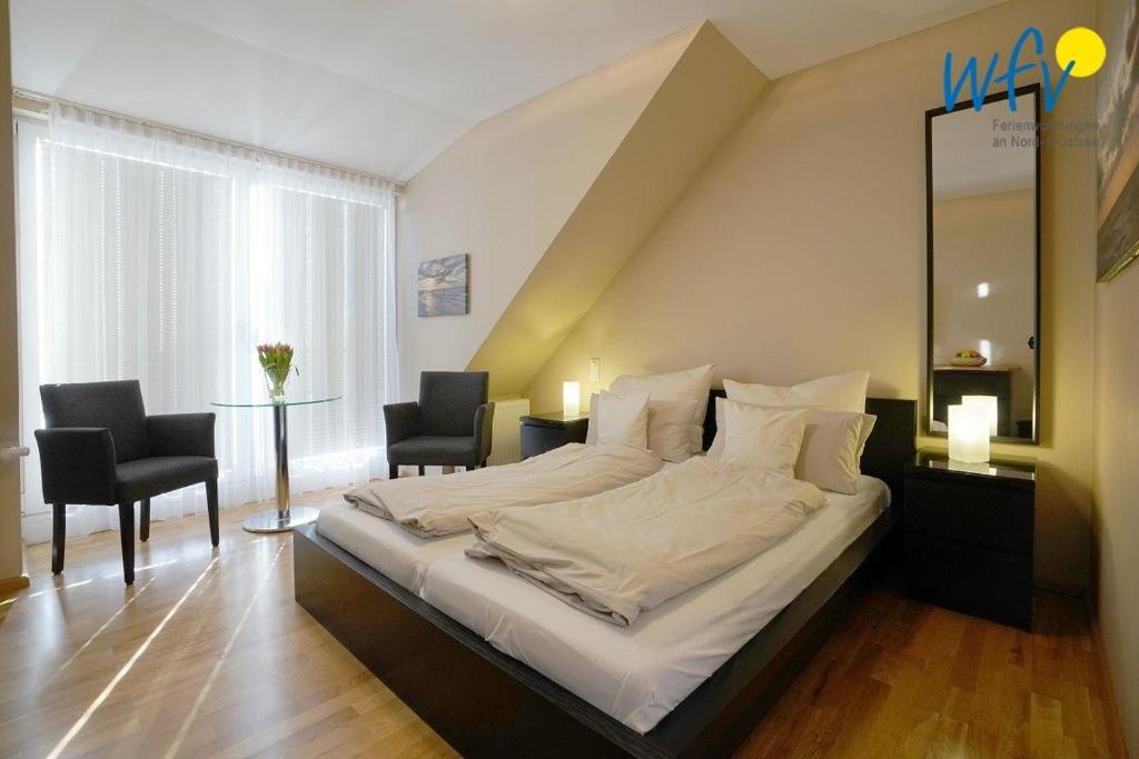 um quarto com uma cama grande, 2 cadeiras e uma mesa em Barons Residenz Borkum Ferienwohnung 7 em Borkum