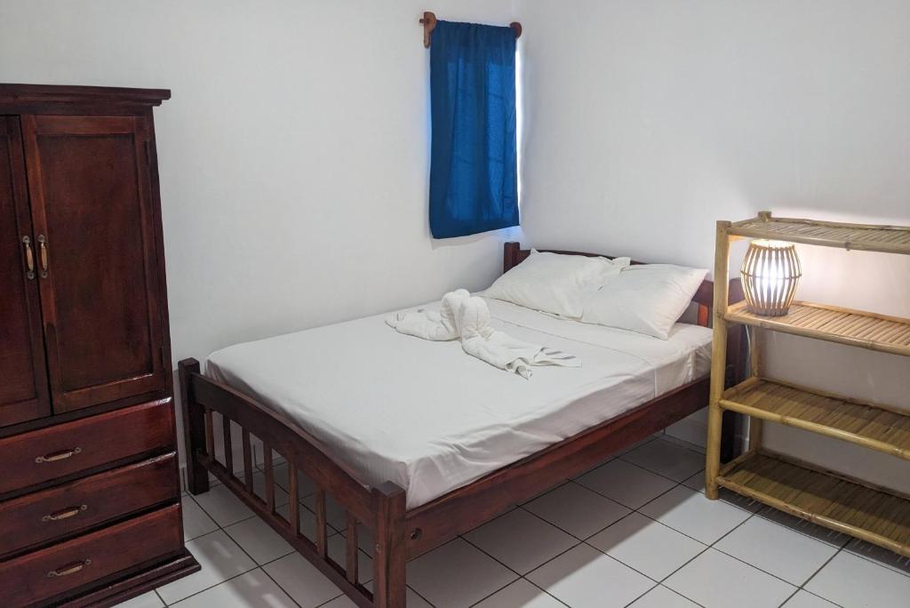 a small bedroom with a bed with a blue curtain at Chale's House Hotel in San Juan del Sur