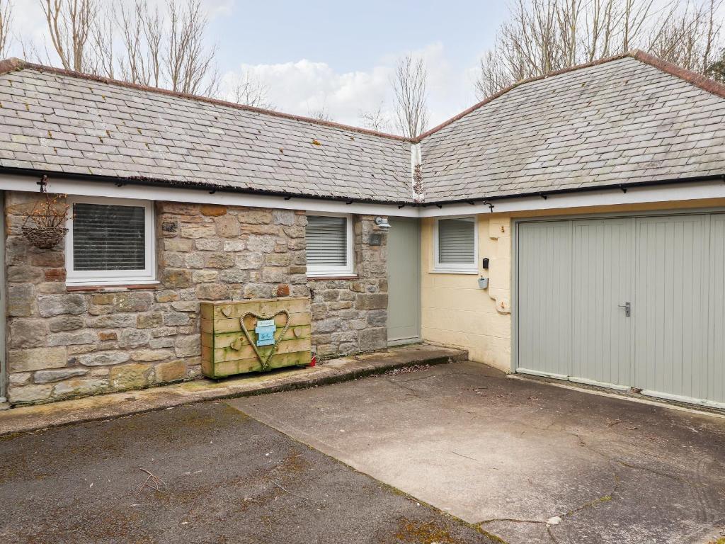 a brick house with a garage and a driveway at Canny Cottage in Morpeth