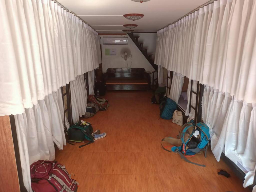 Pakse Backpacker Hostel2023 في باكسي: غرفه وصاله فيها ستائر بيضاء واكياس