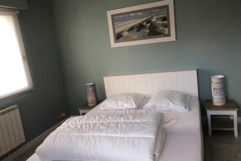 une chambre avec un lit avec des draps blancs et des oreillers dans l'établissement 90m with large terrace near the beach, à Le Touquet-Paris-Plage