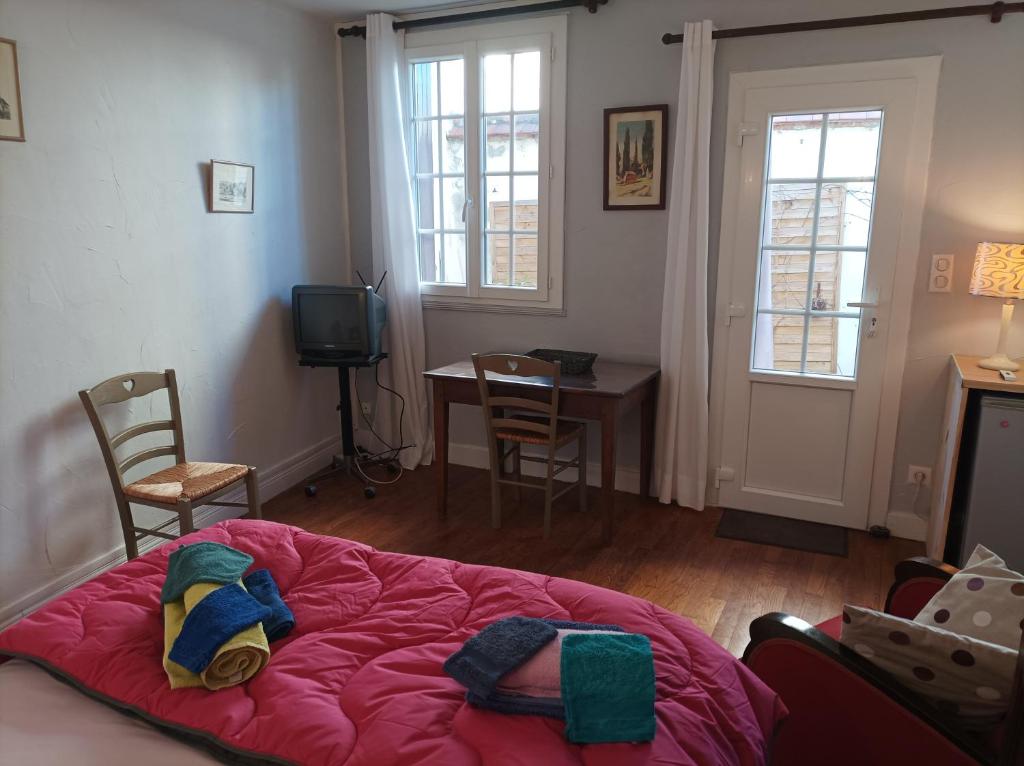 um quarto com uma cama rosa, uma mesa e cadeiras em Au coeur de la cité des Bourbons em Moulins