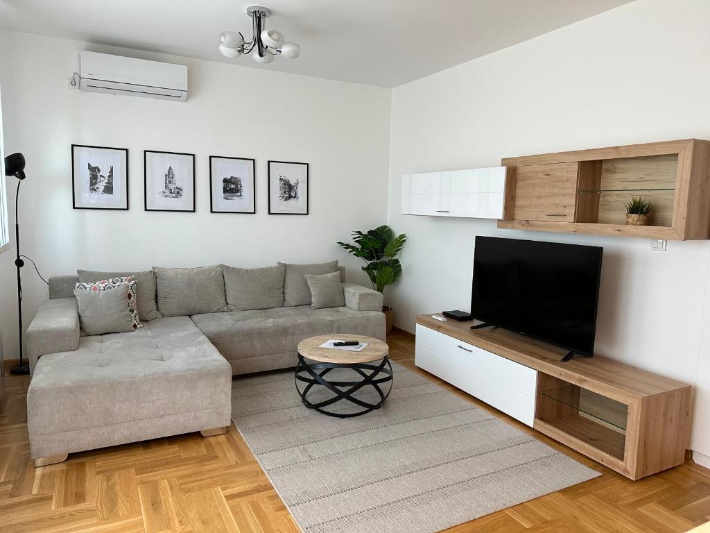 uma sala de estar com um sofá e uma televisão de ecrã plano em Apartment Aura em Belgrado