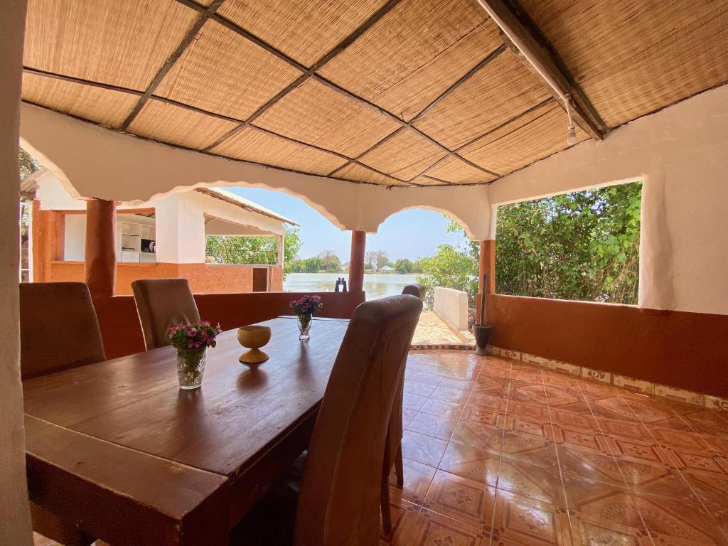 a dining room with a wooden table and chairs at Finfoot Lodge in Lamin Koto