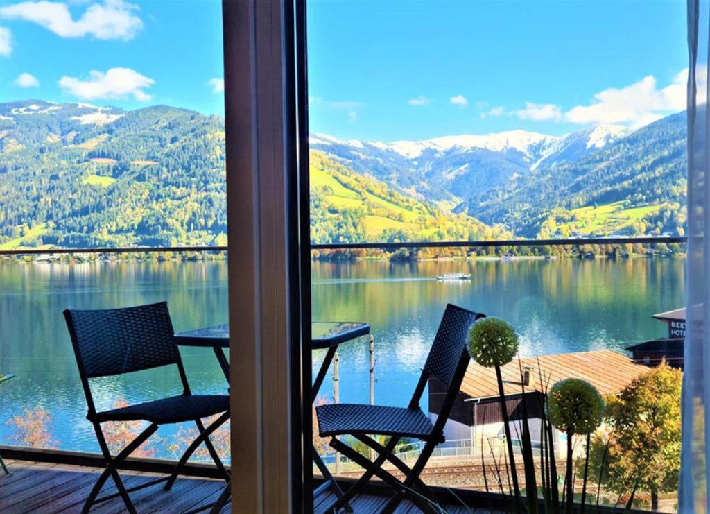 two chairs and a table on a porch with a view of a lake at Alpin & See Resort - Pinzgau Holidays in Zell am See