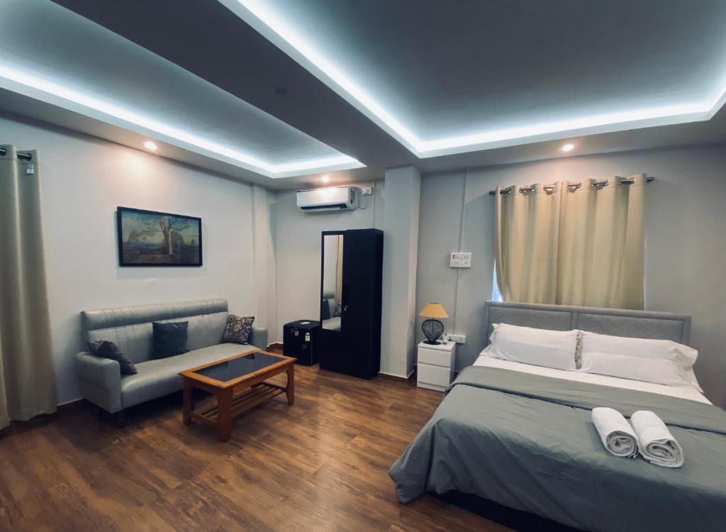 een slaapkamer met een bed en een bank bij SunsetHomes A luxurious studio apartment in Imphal