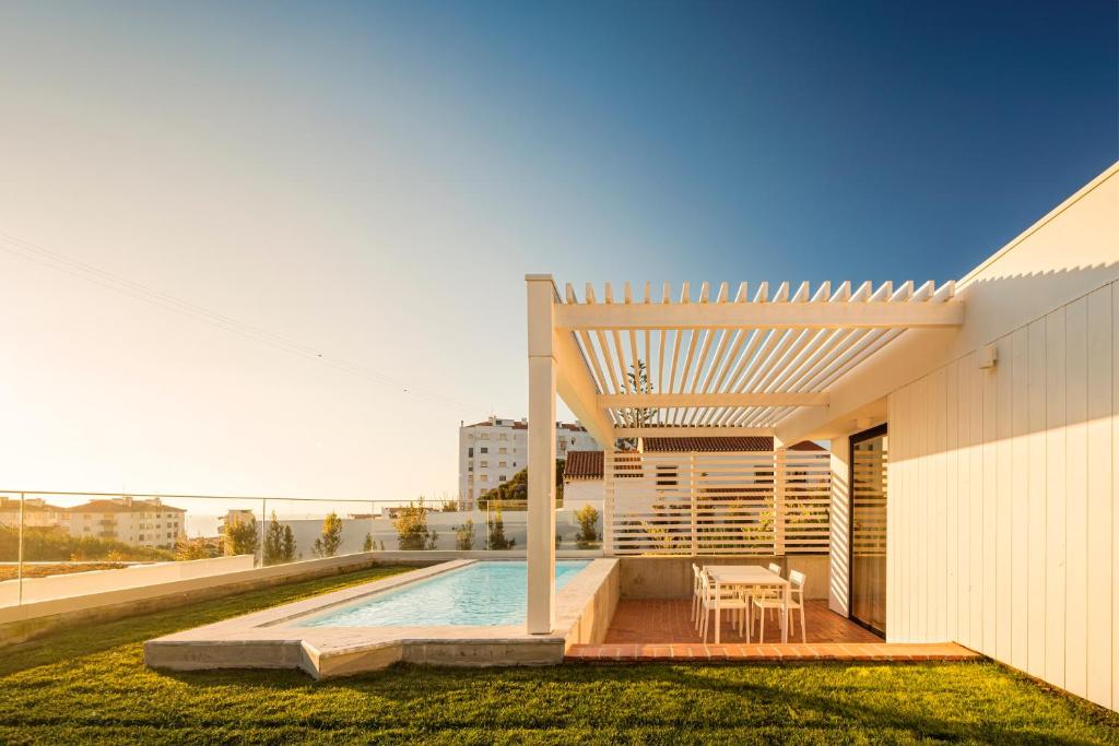 a house with a swimming pool and a pergola at Ericeira Prime Villas in Ericeira
