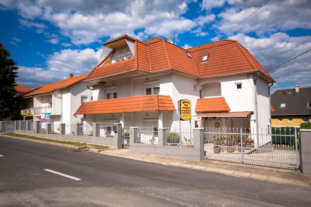 a white house with an orange roof on a street at Williams Haus in Hévíz