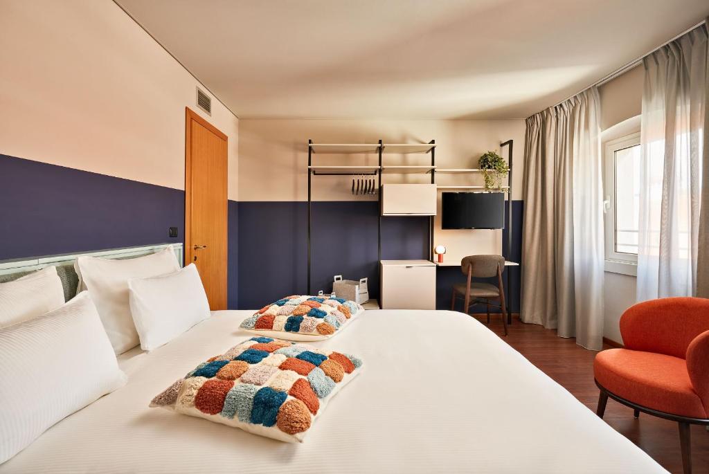 a hotel room with a large white bed and a chair at Urbanauts Studios Minelli in Trieste