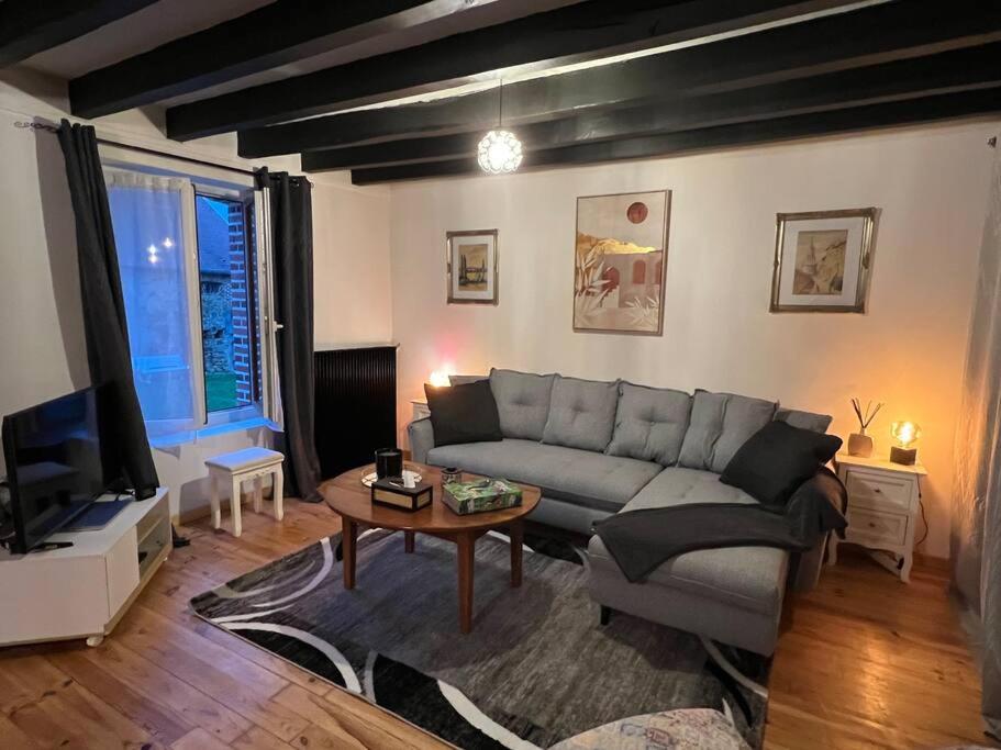een woonkamer met een bank en een tv bij Charmante maison berrichonne in Gargilesse-Dampierre