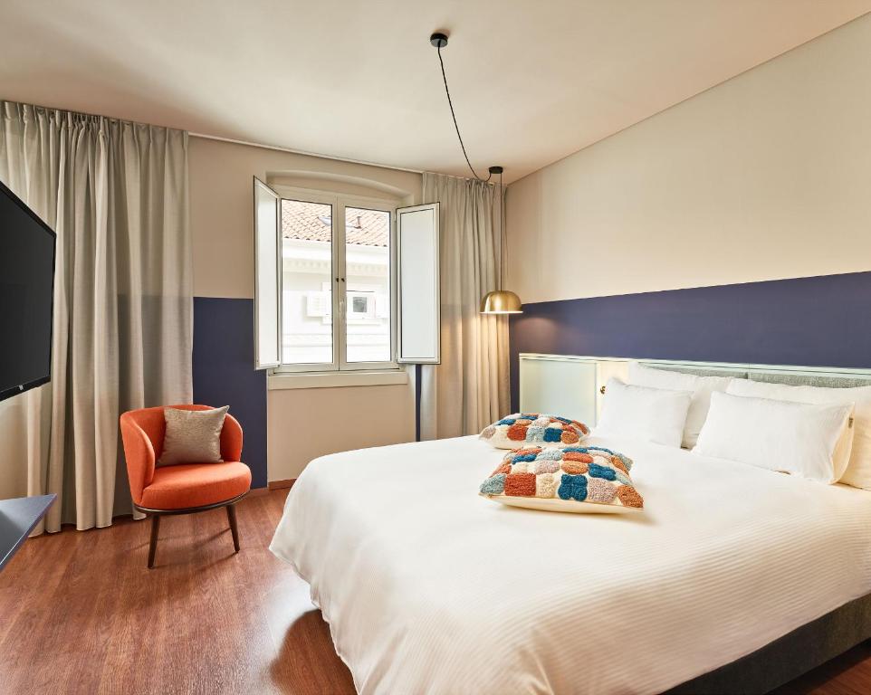トリエステにあるURBANAUTS STUDIOS Minelliの大きなベッドと椅子が備わるホテルルームです。