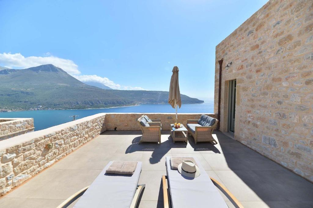 a patio with a view of the water and mountains at Akrolithi Boutique Hotel & Suites in Oitylo