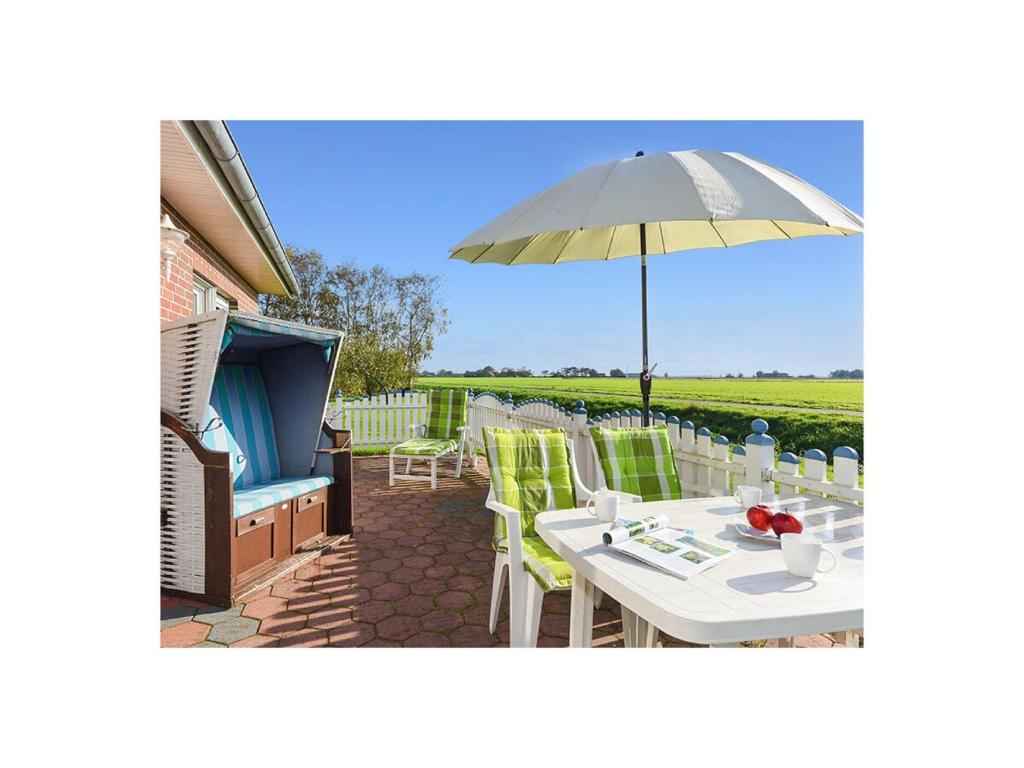 une terrasse avec une table et un parasol dans l'établissement Muschel 1, à Bensersiel