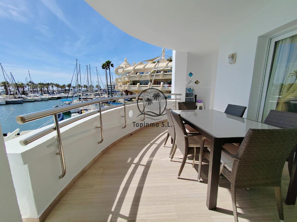 d'un balcon avec une table, des chaises et un bateau. dans l'établissement Cozy corner 2 bedroom apartment on new Island complex in marina harbour, à Benalmádena