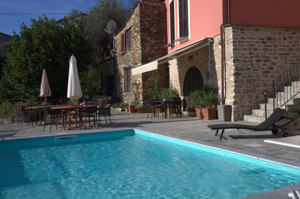 ドルチェードにあるAppartamenti Chiarinaのテーブルと椅子のある家の隣にスイミングプールがあります。