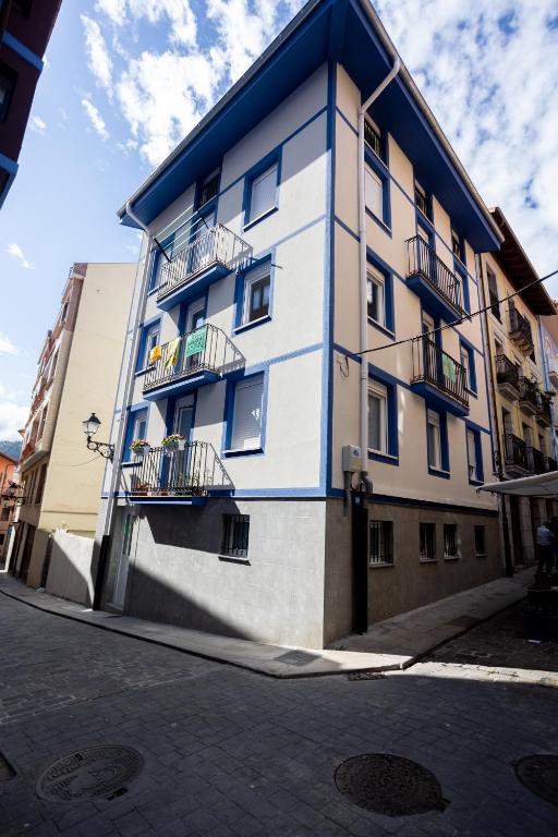 biało-niebieski budynek z balkonami przy ulicy w obiekcie El Ancla de Bermeo By Urdaibai Rentals w mieście Bermeo