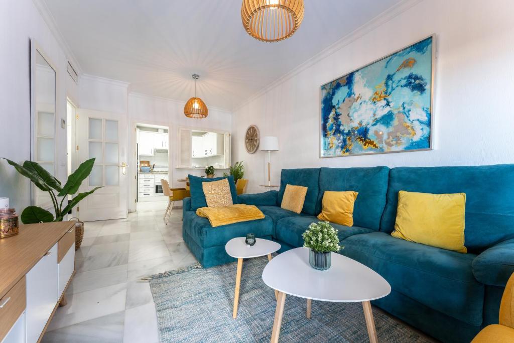 sala de estar con sofá azul y almohadas amarillas en Doña Sofía, en Fuengirola
