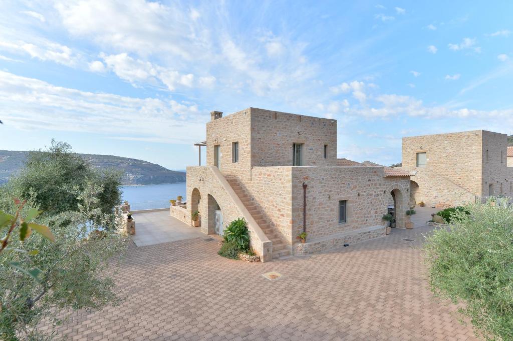 an external view of a large brick building with a lake at Akrolithi Boutique Hotel & Suites in Oitylo