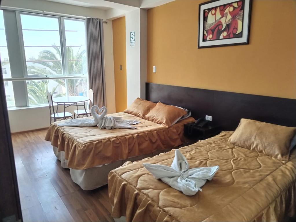 a hotel room with two beds and a table at Hotel Dubái in Tacna
