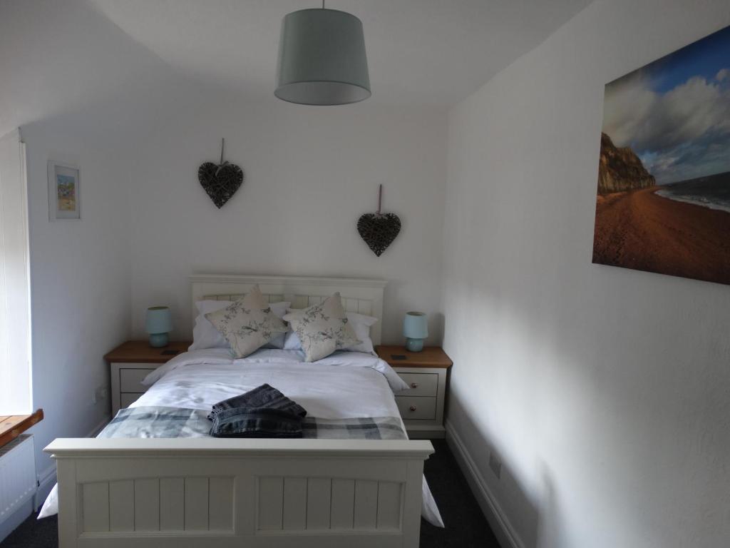 sypialnia z białym łóżkiem z sercami na ścianie w obiekcie Staddlestones Cottage w mieście Bridport