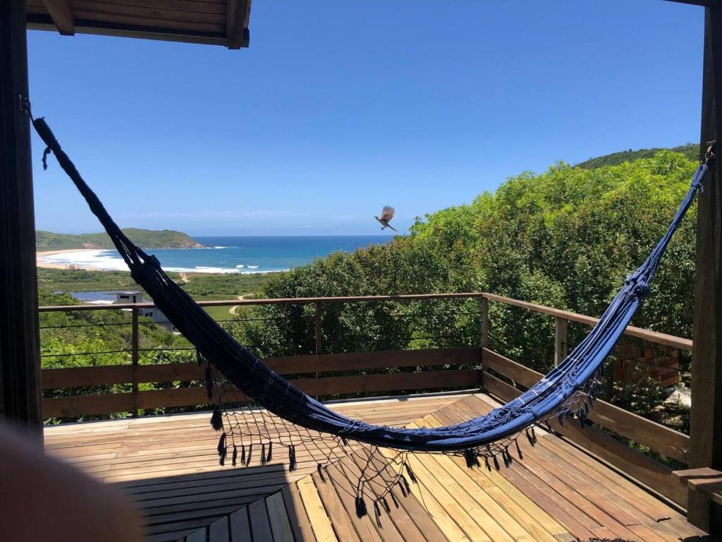 a hammock on a deck with a view of the ocean at Praia do Silveira Canto Sul in Garopaba