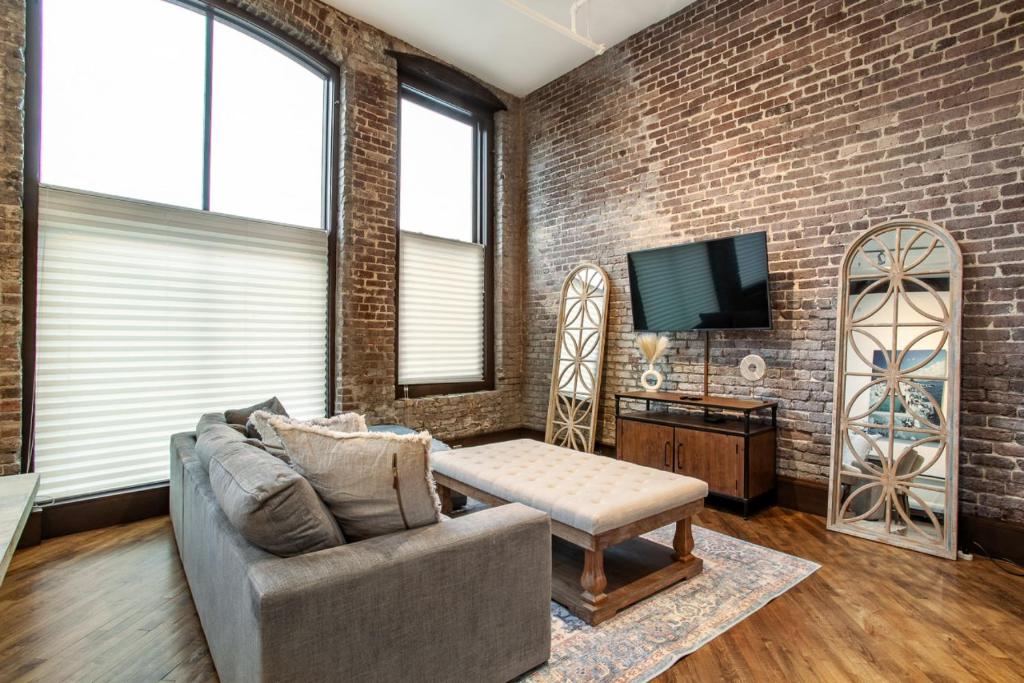 a living room with a couch and a brick wall at Jackson Jewel - Downtown Suite in Knoxville